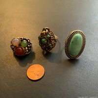 Three vintage rings arranged with a penny for size comparison, showing overall design and condition