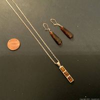 Full view of necklace and earrings with a penny for scale showing the size of jewelry pieces.