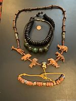 Top view photo showing entire set of four jewelry pieces on dark surface with penny for scale.