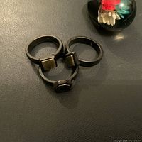 Three vintage black metal stacking rings with square accents arranged together on black surface.