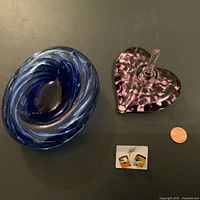 Two Murano glass trinket dishes and a pair of earrings with a penny for size reference shown on black surface.
