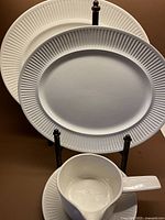 Front view of 2 oval platters and gravy boat with drip plate arranged with platters on stand.