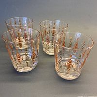 Four mid-century lowball glasses with cinnamon, chocolate and gold pointed geometric decoration arranged in a cluster