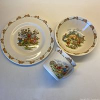 Top-down view of the full 3-piece baby dish set: small plate, bowl, and handled cup arranged closely to show designs and size relation.