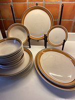 Photo shows a stacked arrangement of plates including dinner, salad, and cereal bowls, with some plates held upright by display stands to show the pattern.