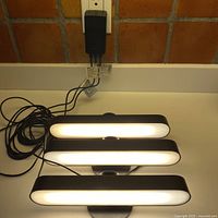 Three rechargeable wall lamps powered and lit up to show working condition with power cord visible.