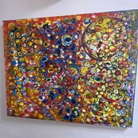 Full view of colorful abstract painting with many spheres on canvas hung on wall.