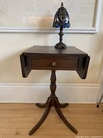 Front view of vintage solid wood side table with two drop leaves folded down and drawer visible.
