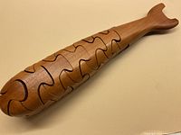 Curved wooden whale puzzle made from teak with visible interlocking puzzle piece seams, showing the top and side profile.