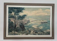 Full view of framed oil painting featuring coastal landscape with trees and ocean waves.