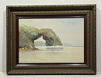 Full frontal view of framed watercolor painting showing coastal rock arch, sandy foreground and frame.
