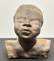 Front view of the terra cotta tribal style head sculpture showing facial details and neck/shoulders.