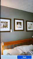 Three framed and matted black and white photos hung on a grey wall above a wooden bedframe. From left to right the images portray a man, a woman wearing a tiara likely Audrey Hepburn, and an architectural building.