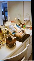 Photo of bathroom countertop with white chair, multiple bottles, and containers including dental and bath supplies