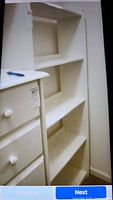 Photo showing front view of a solid white bookshelf next to a white dresser. Four shelves are visible and the bookshelf is placed against a corner wall.