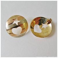 Front view of one gold earring showing tri-colour bands and star and heart cut outs.