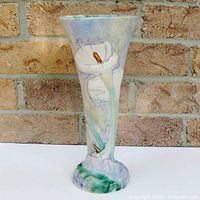 Full front view of trumpet vase showing raised calla lily on textured multicolor background.