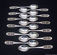 Overhead view of all 12 spoons arranged in rows on black background