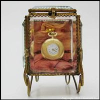 Front view of ormolu frame and bevelled glass vitrine showcasing pink silk interior and pocket watch hook