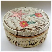 Front three-quarter view of round box showing star and flower inlay on lid and woven sides.