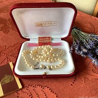 Vintage faux pearl necklace laid in original velvet-lined red box with Majorica logo inside lid; international guarantee card present.