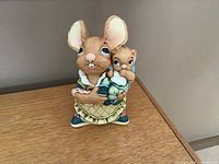 Front view of the mother bunny holding baby bunny figurine, showing detailed eyes, outfits, and delicate handpainting.
