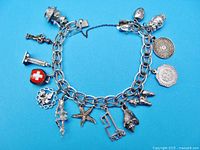 Full view of 7¼” double loop sterling silver bracelet with all 14 charms displayed on blue background