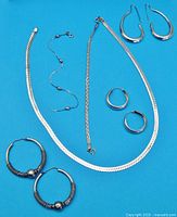 Full view of jewelry collection including necklace, bracelets, and multiple earrings laid on blue background