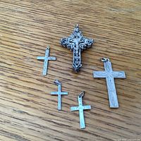All five crosses displayed on a wooden surface showing variety of sizes and designs.