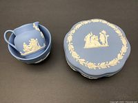 Set of Wedgwood Jasperware cream and sugar and covered pin dish showing classical white relief putti and laurel detailing on light blue matte base.