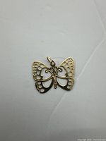 Close-up photo of the delicate 14K gold butterfly pendant front, showing open filigree wing design and attachment loop.