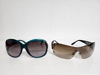Two pairs of vintage sunglasses, one teal frame and one frameless lens style, displayed side by side.