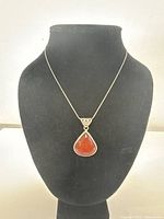 Front view of the necklace on display bust showing the teardrop-shaped carnelian pendant and chain.