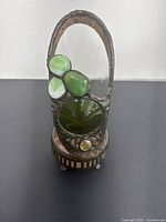 Full front view of the decorative lantern showing clear and green glass accents within metal frame and handle.