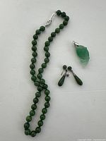 Full set: jade bead necklace, drop earrings, fish pendant laid flat