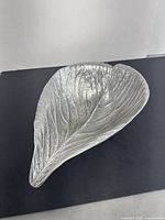 Top and side view showing the elongated leaf shape with detailed vein texture and curved edges.