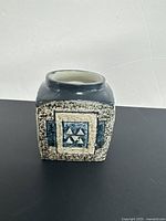 Front view showing triangular relief motif in blue on speckled beige background