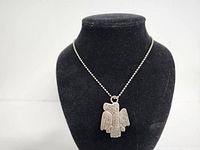 Front view of silver-tone Native American style thunderbird pendant on ball chain necklace displayed on black stand.