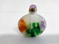 Front view of the natural multi-color jade snuff bottle showing green, orange, and purple colors with purple stopper and gold collar.