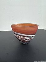 Photo of red and white swirled glass vase from an angled side showing the shape and swirl pattern.
