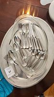 Top view of flatware pieces laid over one serving tray showing forks, spoons, knives clustered together.