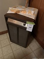 Full view of the Beaumark 30 dehumidifier placed on tiled floor with a fabric cover partially draping over it.