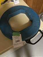 Blue octagonal plastic reel housing for Ideal Tuff-grip Pro Gold Fish Tape, showing top side with brand and model 31-144 markings and black handle.