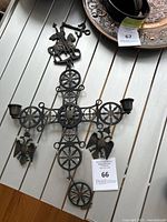 Photo of the large bronze Byzantine cross featuring St. George on horseback, double-headed eagles, and integrated candle holders, placed on a white table surface.
