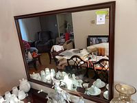 Mirror reflecting the room including furniture and various ceramic decor items placed in front of it.