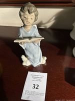 Front view of Lladro porcelain figurine showing angel child kneeling with open book