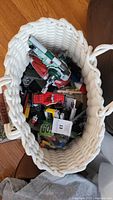 Top view of white woven basket containing multiple LEGO pieces and partially assembled LEGO models.