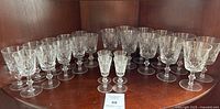 15 Royal Brierley Ascot pattern cut crystal glasses arranged in wooden cabinet, mixing sherry, red wine and aperitif glasses visible