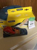 Vintage Stanley small block plane with red handle placed next to original yellow Stanley box showing model number 12-247.