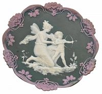 Front view of jasperware wall plaque showing green base, white relief figures of a fairy and cherub, and mauve floral border.
